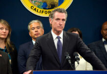 Union Push Tests Newsom’s Nerve Person speaks at podium with California seal behind.