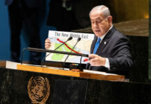 Speaker at UN podium holding a Middle East map