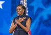 Angry Label Sticks—Michelle Obama Under Fire Person standing in front of American flag smiling