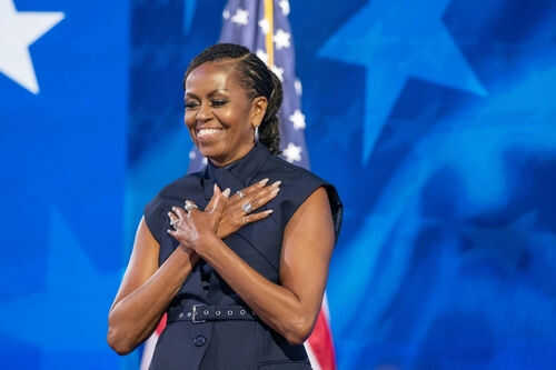 michelle-obama-2507620097 Person standing in front of American flag smiling