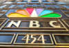 Cable Empire Cracks — Comcast Flinches NBC logo with colorful peacock design.