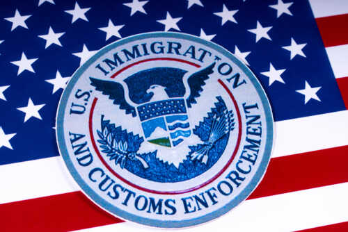 Seal of U.S. Immigration and Customs Enforcement on an American flag background