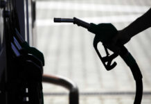 Silhouette of a hand holding a fuel nozzle at a gas station
