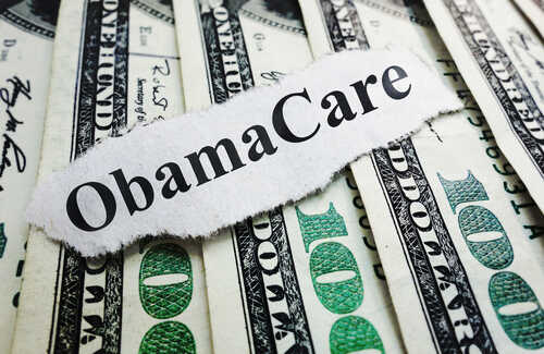 A piece of paper with 'ObamaCare' printed on it placed on top of U.S. dollar bills