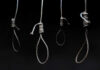 Four nooses hanging against a dark background