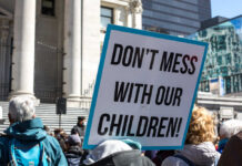 Protest sign held at a rally in an urban square