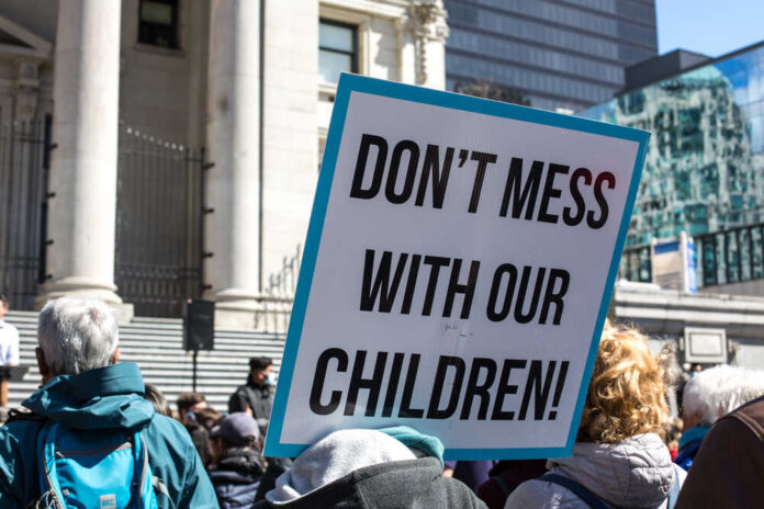 Protest sign held at a rally in an urban square