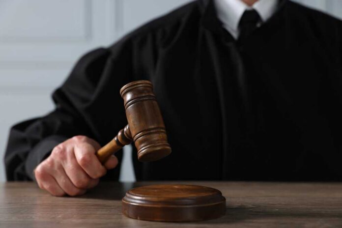 Judge,With,Gavel,Sitting,At,Wooden,Table,,Closeup A judge holding a gavel above a wooden block