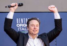 Warren Moves To Stall Musk’s Moonshot Person with a microphone raising hands in celebration