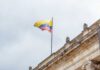Colombian flag atop a neoclassical building against a cloudy sky