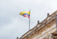 Colombian flag atop a neoclassical building against a cloudy sky