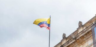 Colombian flag atop a neoclassical building against a cloudy sky