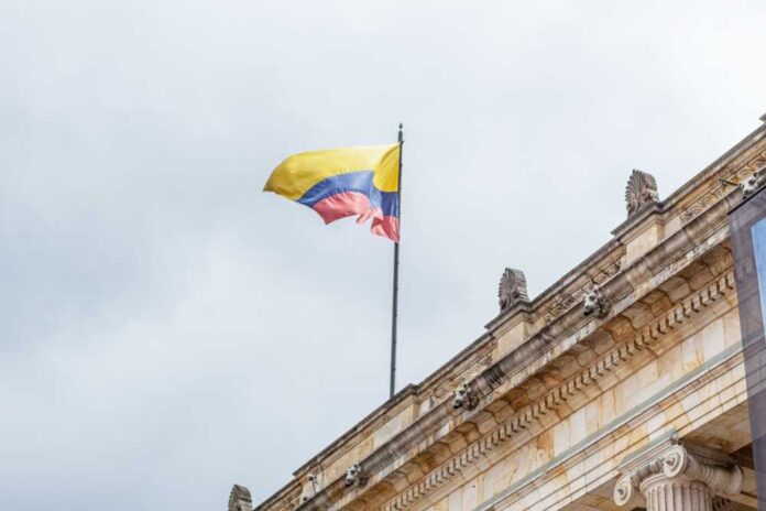 Colombian flag atop a neoclassical building against a cloudy sky