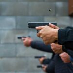 Hands holding pistols at a firing range