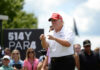 Manhattan Power Seat: Trump’s Controversial Choice Man in red cap and white golf shirt gesturing at a golf event