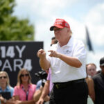 Manhattan Power Seat: Trump’s Controversial Choice Man in red cap and white golf shirt gesturing at a golf event
