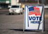 Four GOP Defections Block SAVE Act Vote Here sign with American flag.