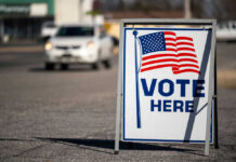 Four GOP Defections Block SAVE Act Vote Here sign with American flag.