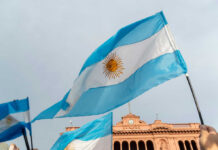 FIFA Hypocrisy Erupts On World Stage Argentinian flag with sun emblem waving above a historic building