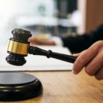 Biden-Era Bust Backfires — Trump DOJ Pays Judge's hand holding a gavel over a sound block