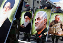 Iran Proxies Cornered—What Breaks First? Demonstrators holding large portraits of military and political figures during a protest