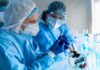 Scientists in protective gear working with a syringe in a laboratory