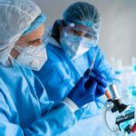 Deadly Ebola Gap Spurs Vaccine Sprint Scientists in protective gear working with a syringe in a laboratory