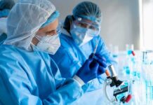 Deadly Ebola Gap Spurs Vaccine Sprint Scientists in protective gear working with a syringe in a laboratory