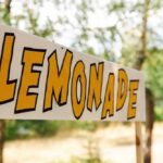 Kids Crush It—Media Botches The Count Lemonade stand sign with bold yellow letters outdoors