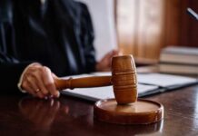 A judge's hand holding a gavel in a courtroom setting