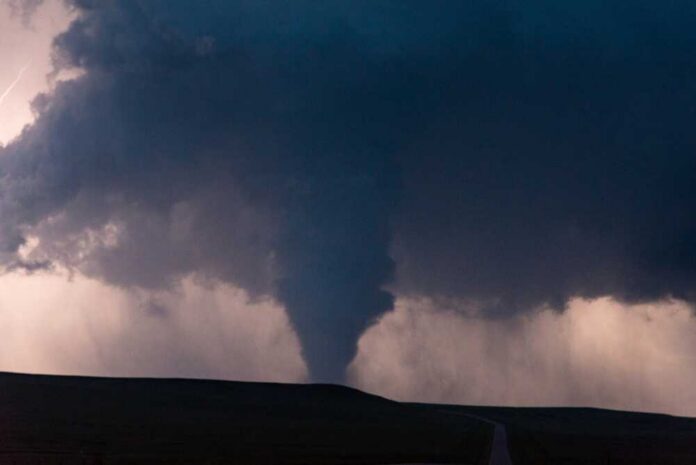 A,Scary,Tornado,Hides,In,The,Darkness,Of,Night,Below A tornado forming under dark storm clouds with lightning in the background