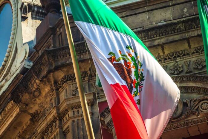 Mexican,Flag,On,Building,In,Mexico,City Mexican flag waving in front of an ornate stone building