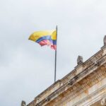 Colombian flag atop a neoclassical building against a cloudy sky