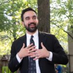 Taxpayers Brace: Reparations Machine Starts Man in suit speaking with hands on chest outdoors
