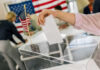Senate Standoff Risks 2026 Chaos Hand placing ballot in box with American flag nearby