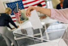 Senate Standoff Risks 2026 Chaos Hand placing ballot in box with American flag nearby