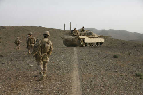 Soldiers walking with armored tank in desert landscape