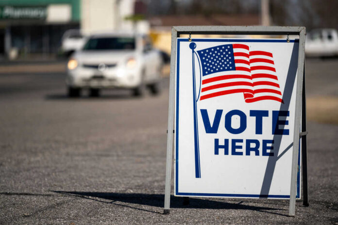 Vote Here sign with American flag.