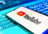 YouTube app on smartphone over illuminated laptop keyboard