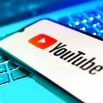 YouTube app on smartphone over illuminated laptop keyboard