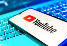 YouTube app on smartphone over illuminated laptop keyboard
