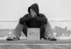 Person sitting holding sign that says help
