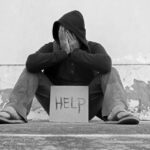 Person sitting holding sign that says help