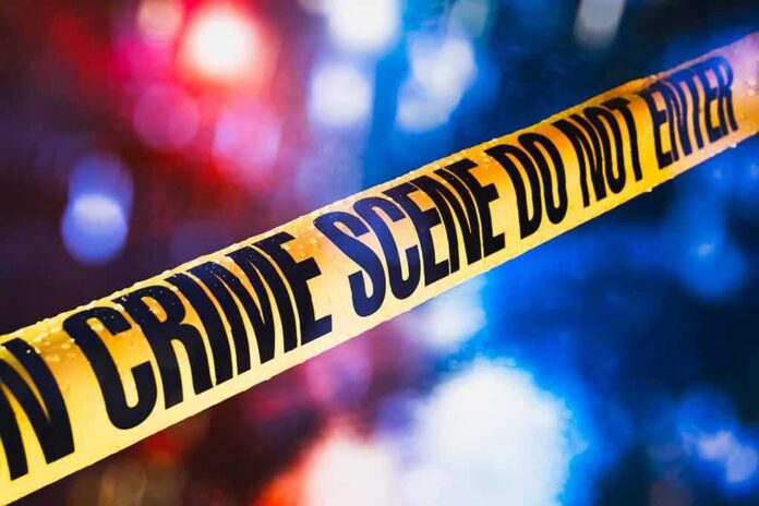 shutterstock_1019775253 yellow crime scene tape with blurred police lights