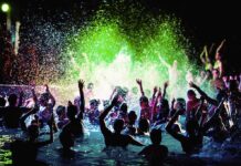 Crowd dancing in a pool under colorful lights