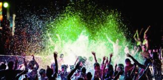 Crowd dancing in a pool under colorful lights