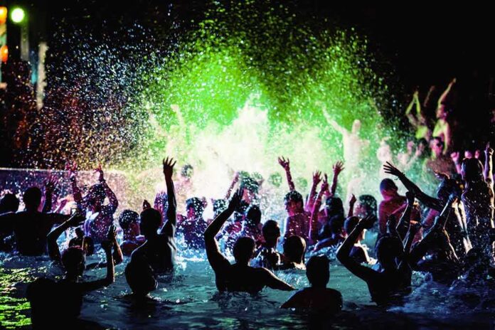 shutterstock_1027724968 Crowd dancing in a pool under colorful lights
