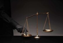 Judge FREEZES Trump TPS Kill Switch Golden balance scale with gloved hand pressing one pan
