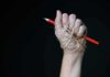 Hand wrapped in twine gripping a red pencil