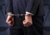 Shocking USDA Nepotism: Money Loops Back Businessperson in handcuffs with hands behind back